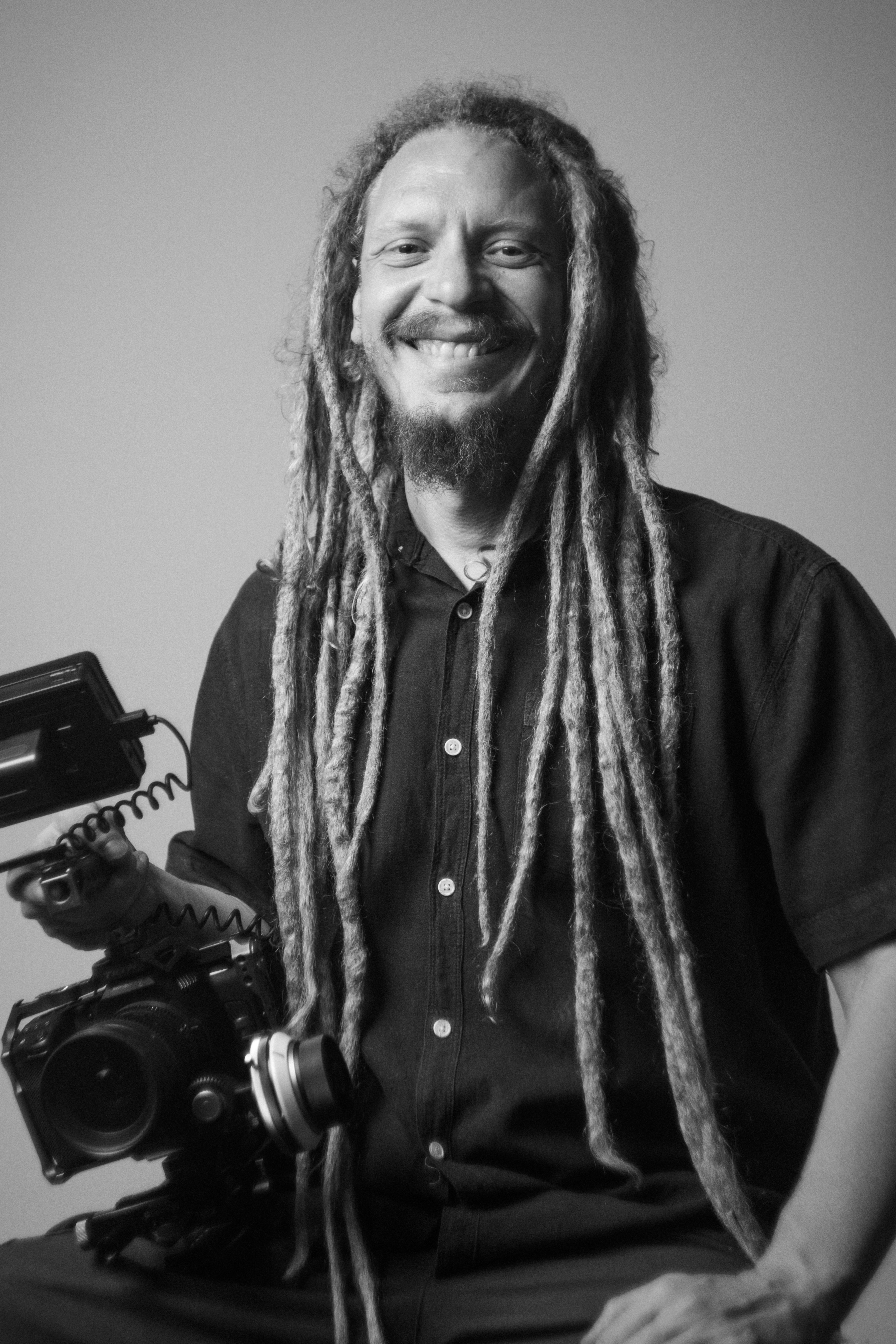 Retrato em preto e branco de Ricardo Roque com sua câmera